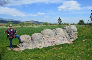Woman standing with foot on rock formation resembling five giant toes sticking out of the ground.